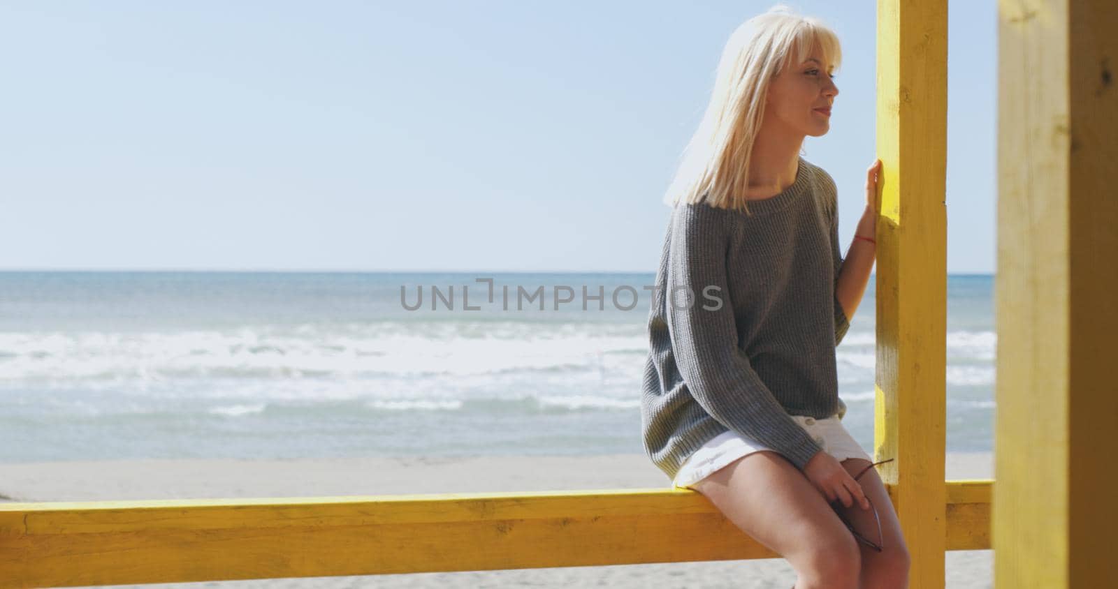 Young woman on the beach. The girl enjoying the warm autumn day. Portrait of beautiful girl near the water