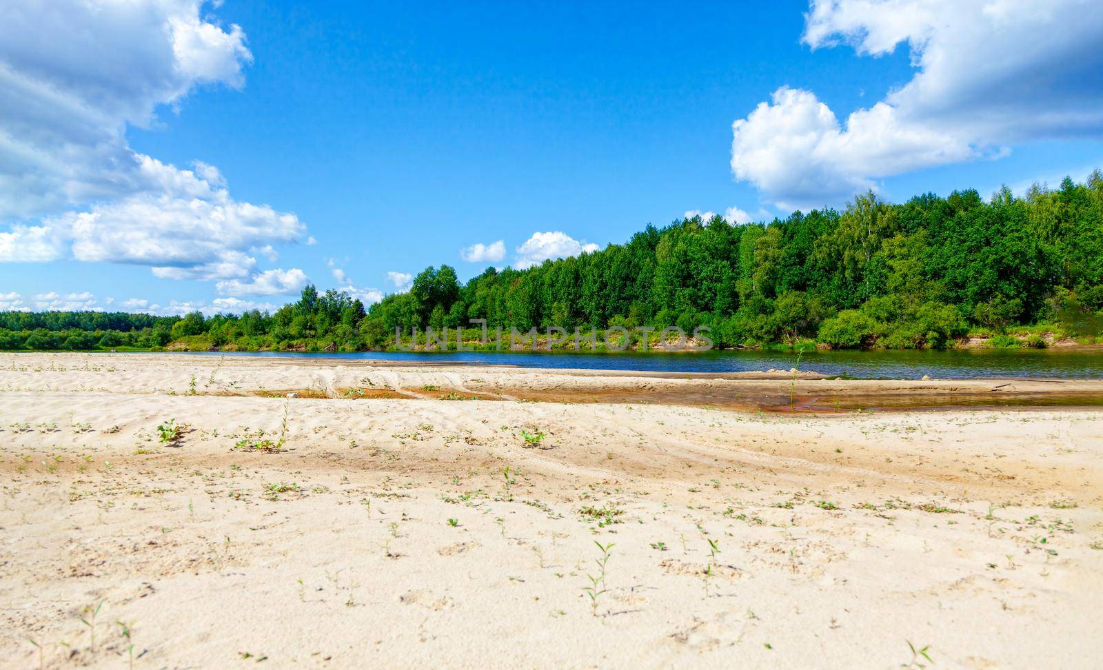 Wild sandy beach near the river on a fine summer day. Only blue sky, sand and a quiet river. Russia, Kostroma region, Kozionikha village. The concept of tourism, native land.