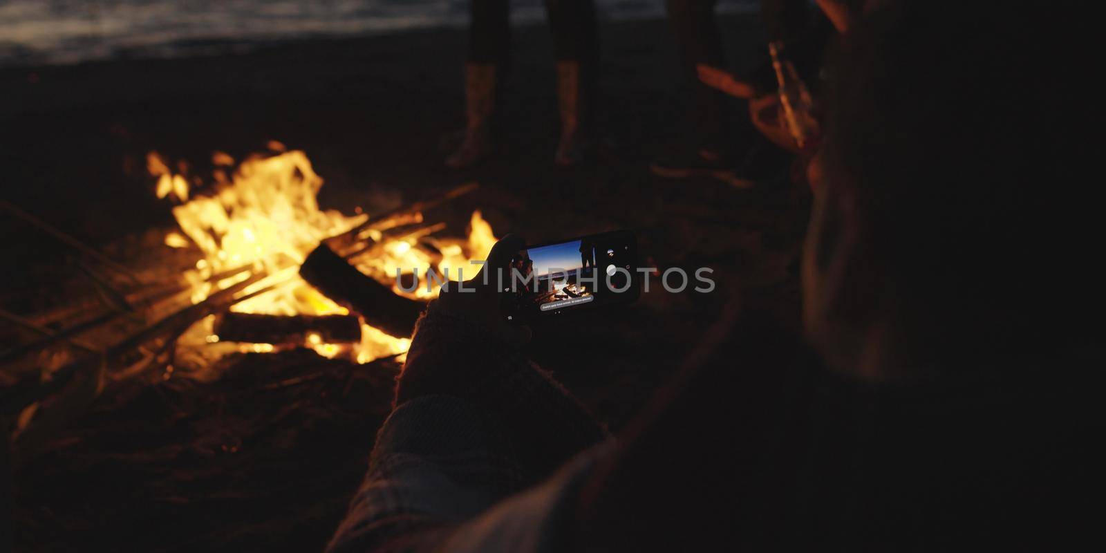 Couple taking photos beside campfire on beach by dotshock