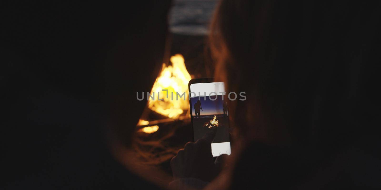 Couple taking photos beside campfire on beach by dotshock