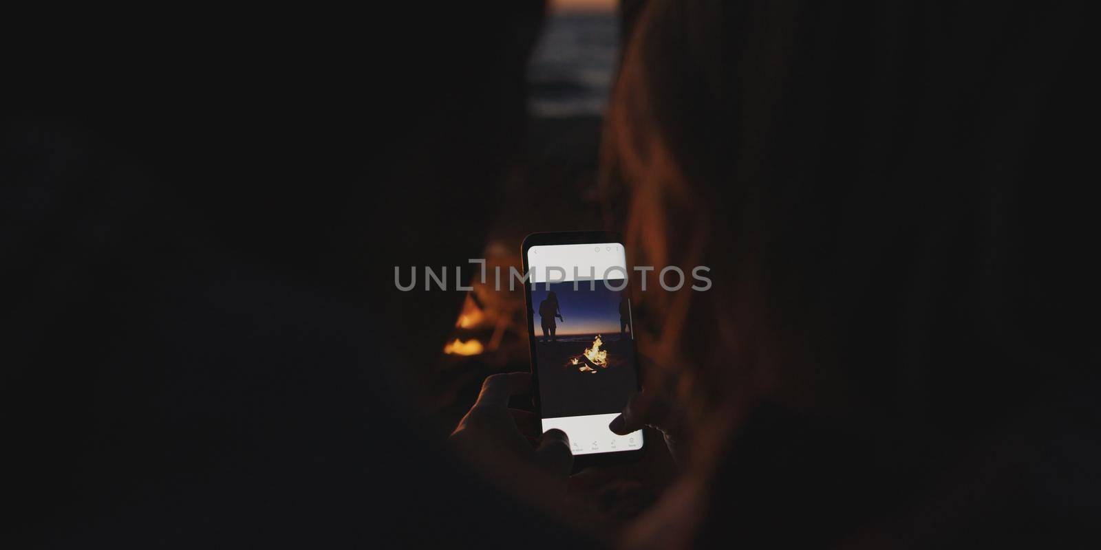 Couple taking photos beside campfire on beach by dotshock