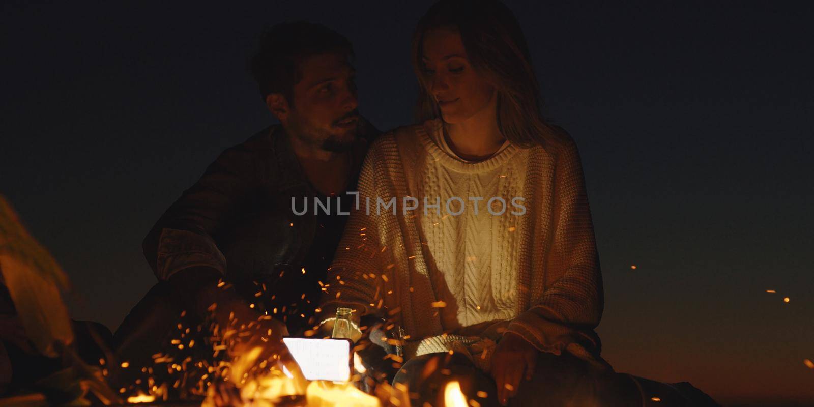 Couple enjoying with friends at night on the beach by dotshock