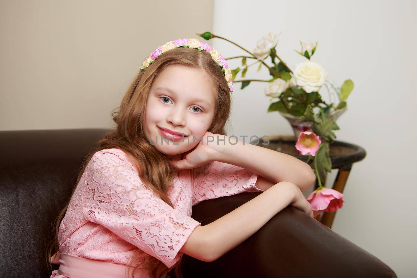 Happy little girl with a bouquet of flowers sitting on the couch. The concept of a holiday, a spring mood.