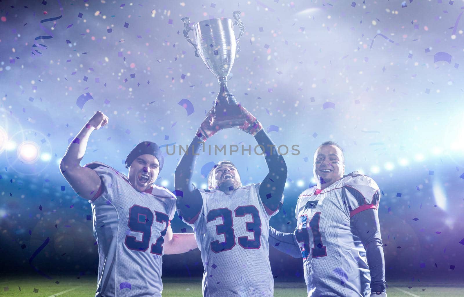 happy american football team with trophy celebrating victory in the cup final on big modern stadium with lights and flares at night