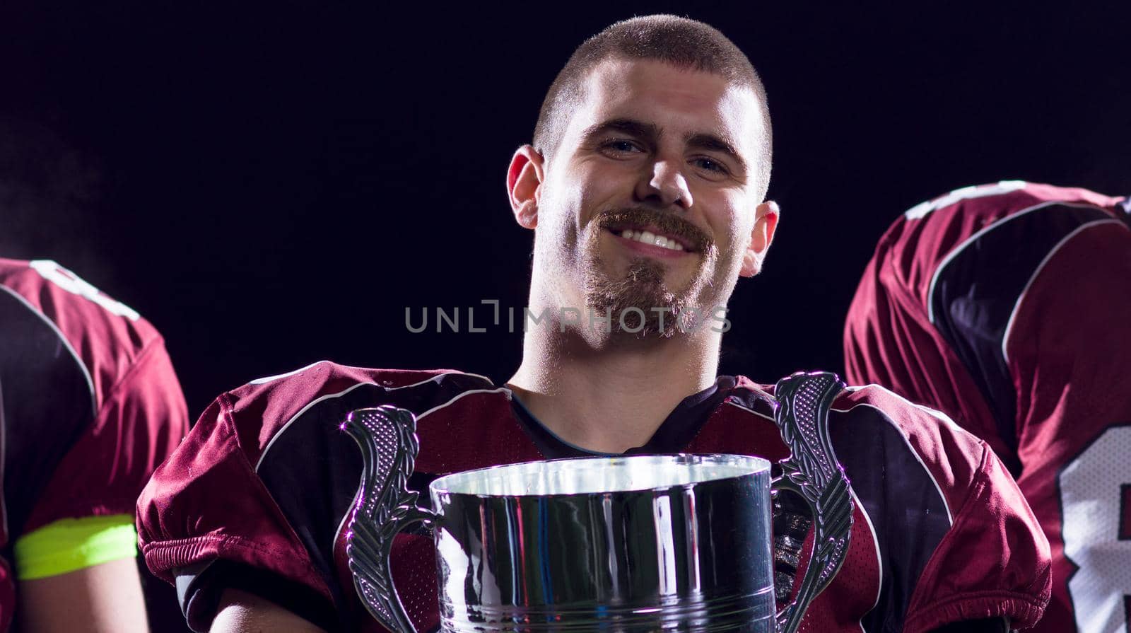 happy american football team with trophy celebrating victory on night field