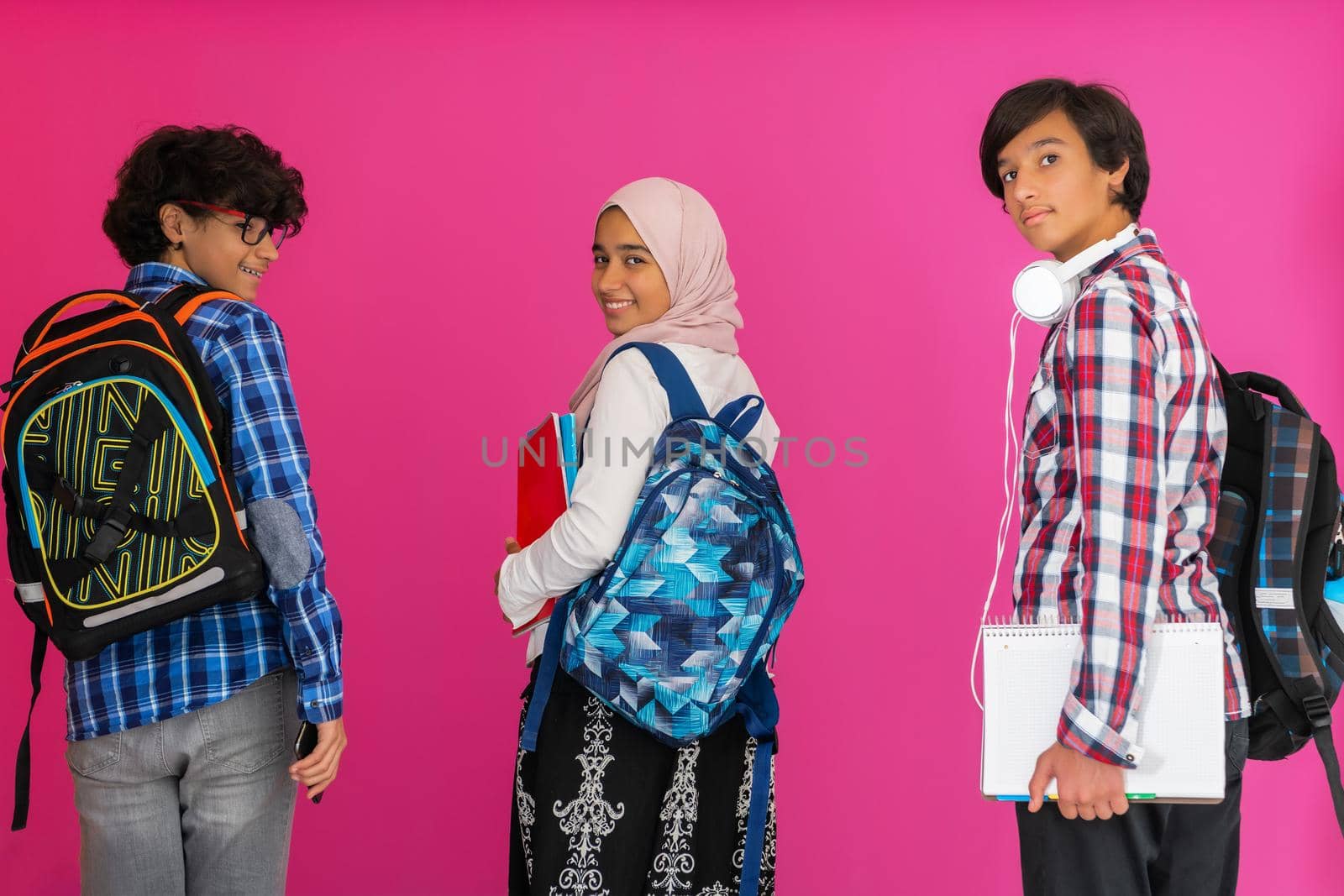 A group of Arab teenagers, a student team walking forward into the future and back to school the concept of a pink background. The concept of successful education for young people. Selective focus by dotshock