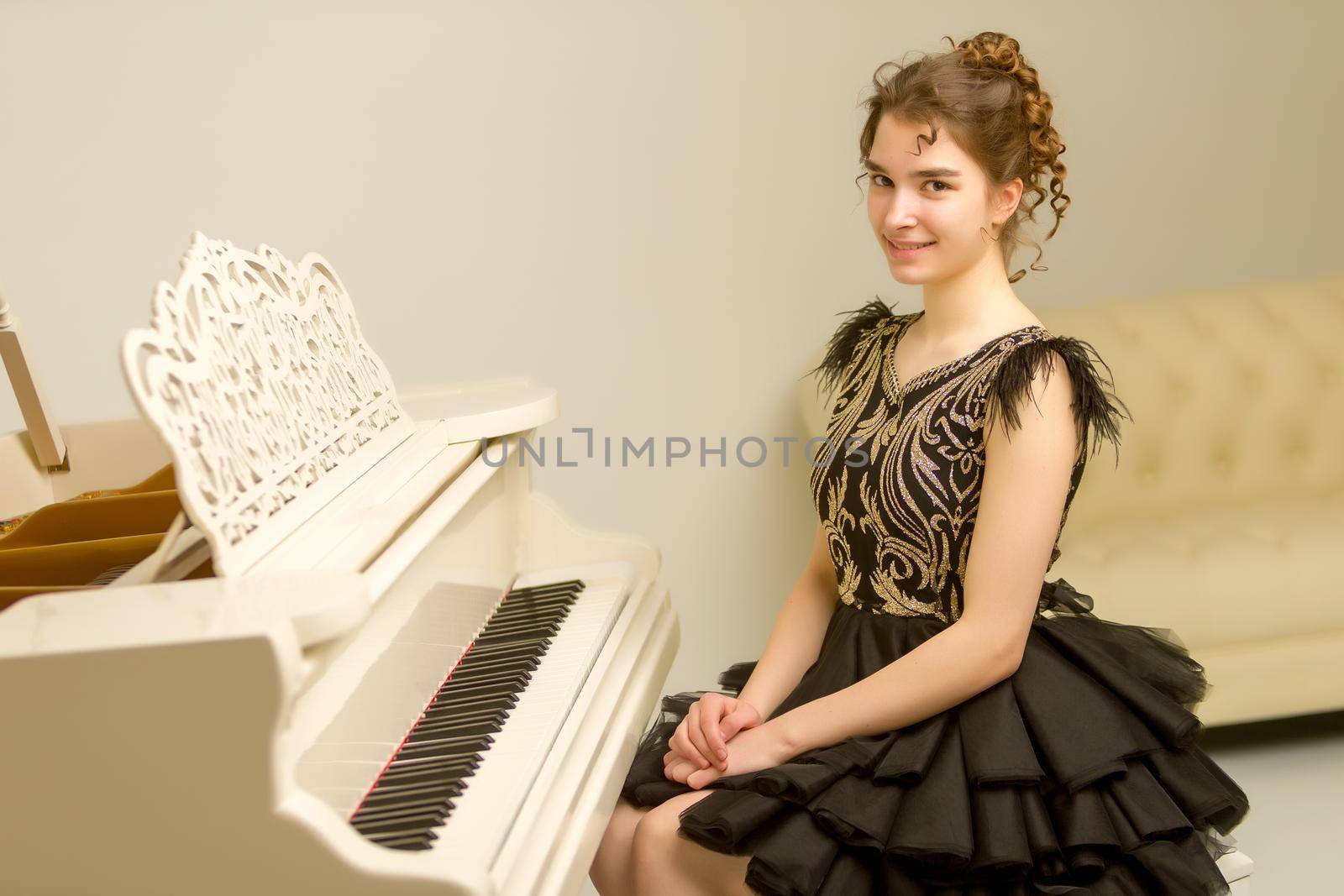 A teenage girl is playing on a white grand piano. The concept of creative development of personality, music education.