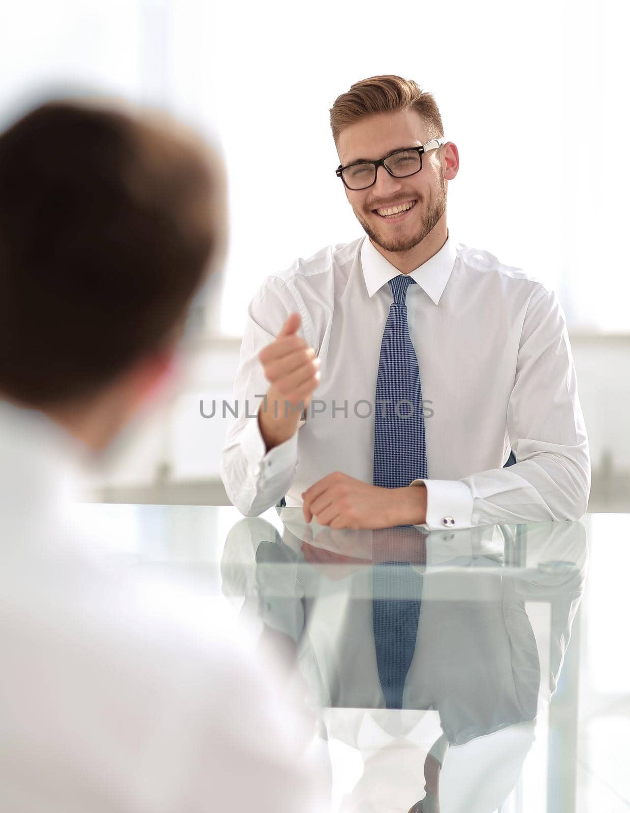 Manager talks to the employee sitting at his Desk.business concept