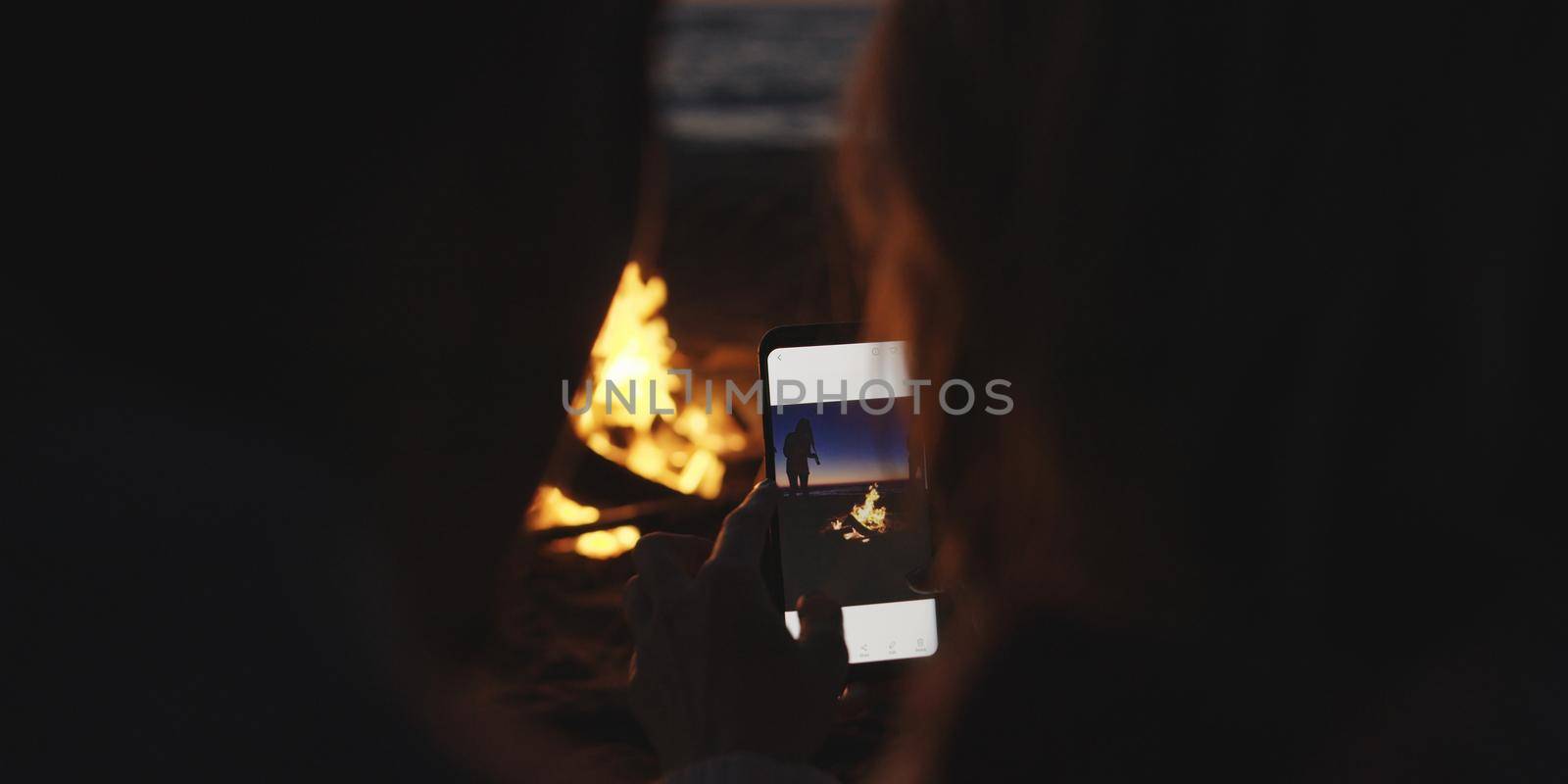 Couple taking photos beside campfire on beach by dotshock