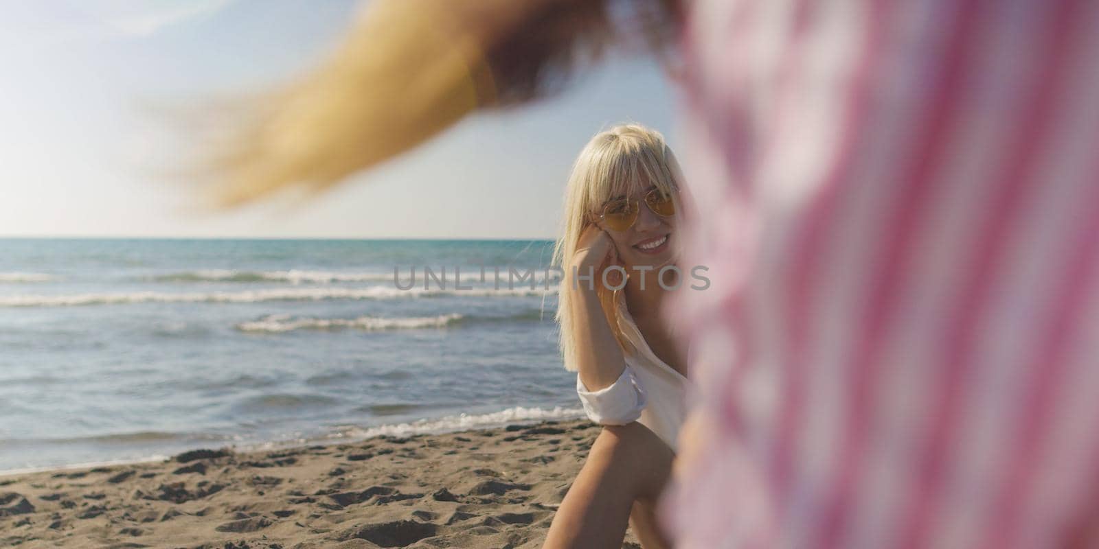 Two Girl Friends Taking Photo with Smartphone On Empty Beach during autumn day