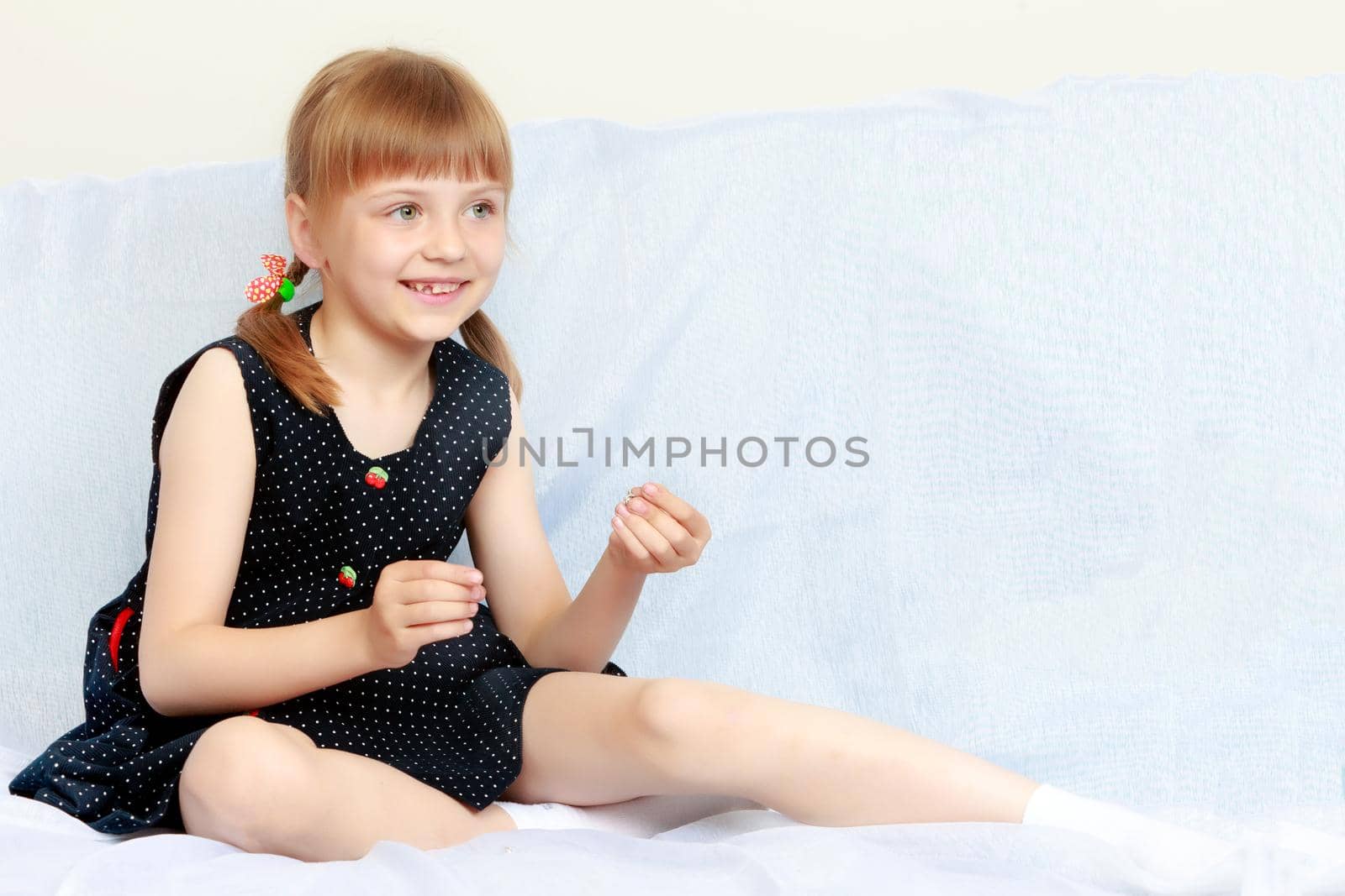 A nice little girl is putting on earrings. The concept of a holiday, beauty, fashion, spiritual development of a child.