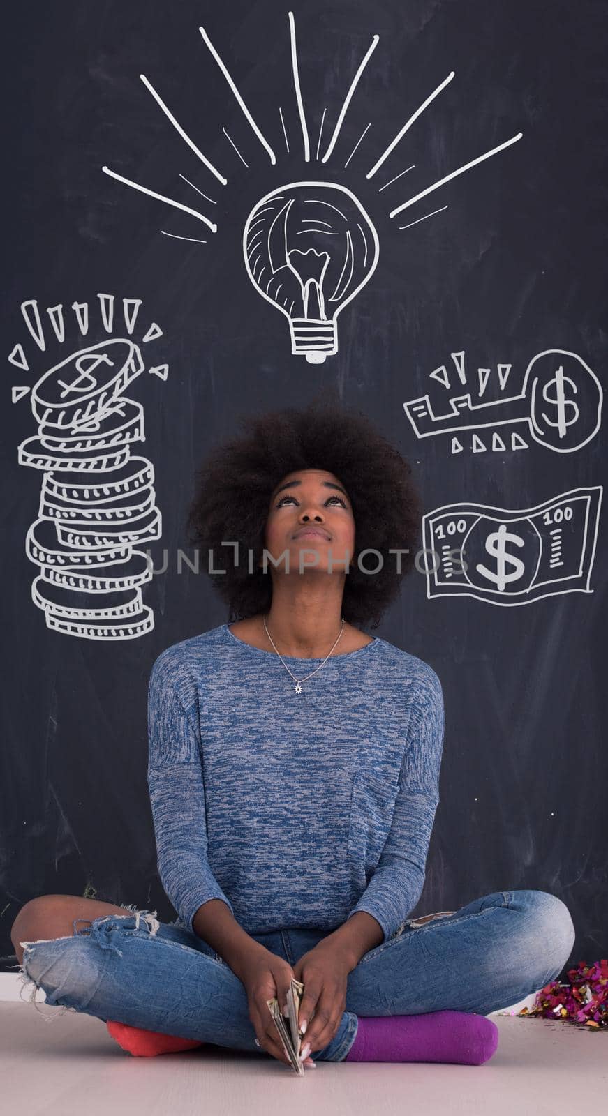 portrait of a beautiful friendly African American woman with a curly afro hairstyle and lovely smile sitting isolated on a gray background