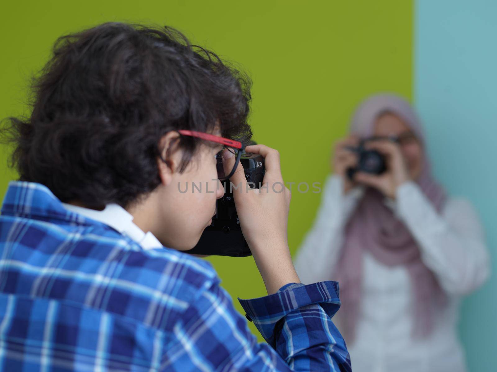 Portrait of  male Photographer in blue shirt holding old analog slr art camera while standing against cyan background