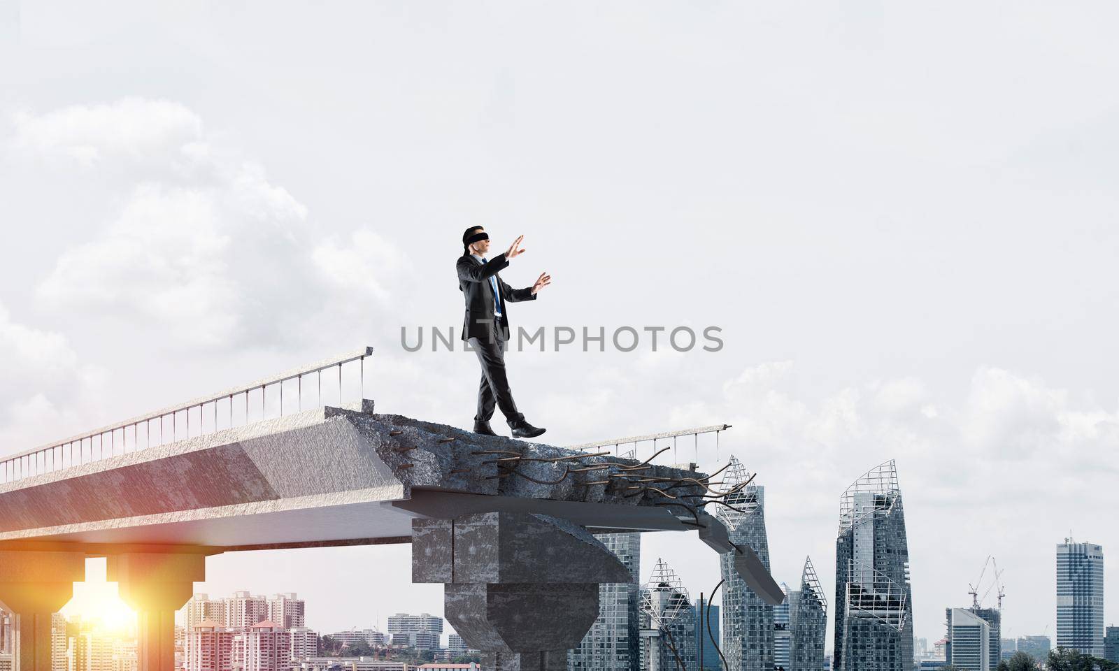 Businessman walking blindfolded on concrete bridge with huge gap as symbol of hidden threats and risks. Cityscape and sunlight on background. 3D rendering.