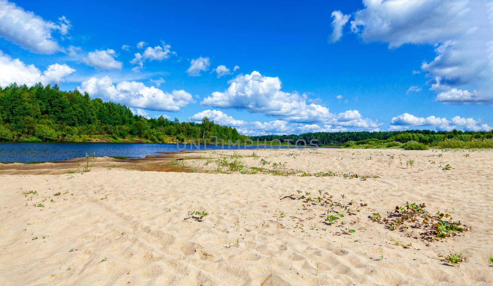 Wild sandy beach near the river on a fine summer day. Only blue sky, sand and a quiet river. Russia, Kostroma region, Kozionikha village. The concept of tourism, native land.