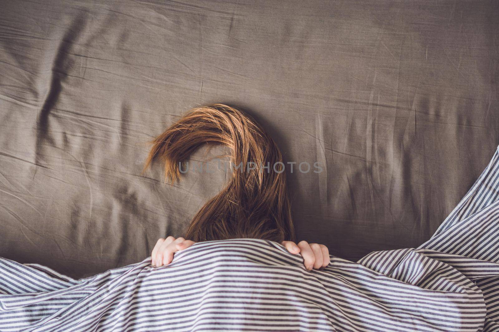 Beautiful young woman lying down in bed and sleeping, top view. Do not get enough sleep concept.