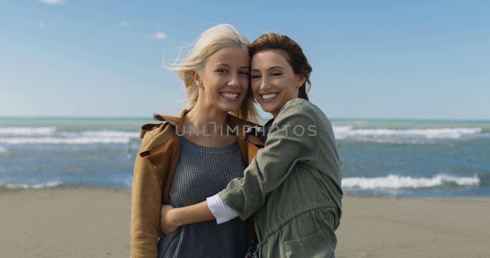 two cute young women smiling and enjoying life on an autumn walk along the ocean