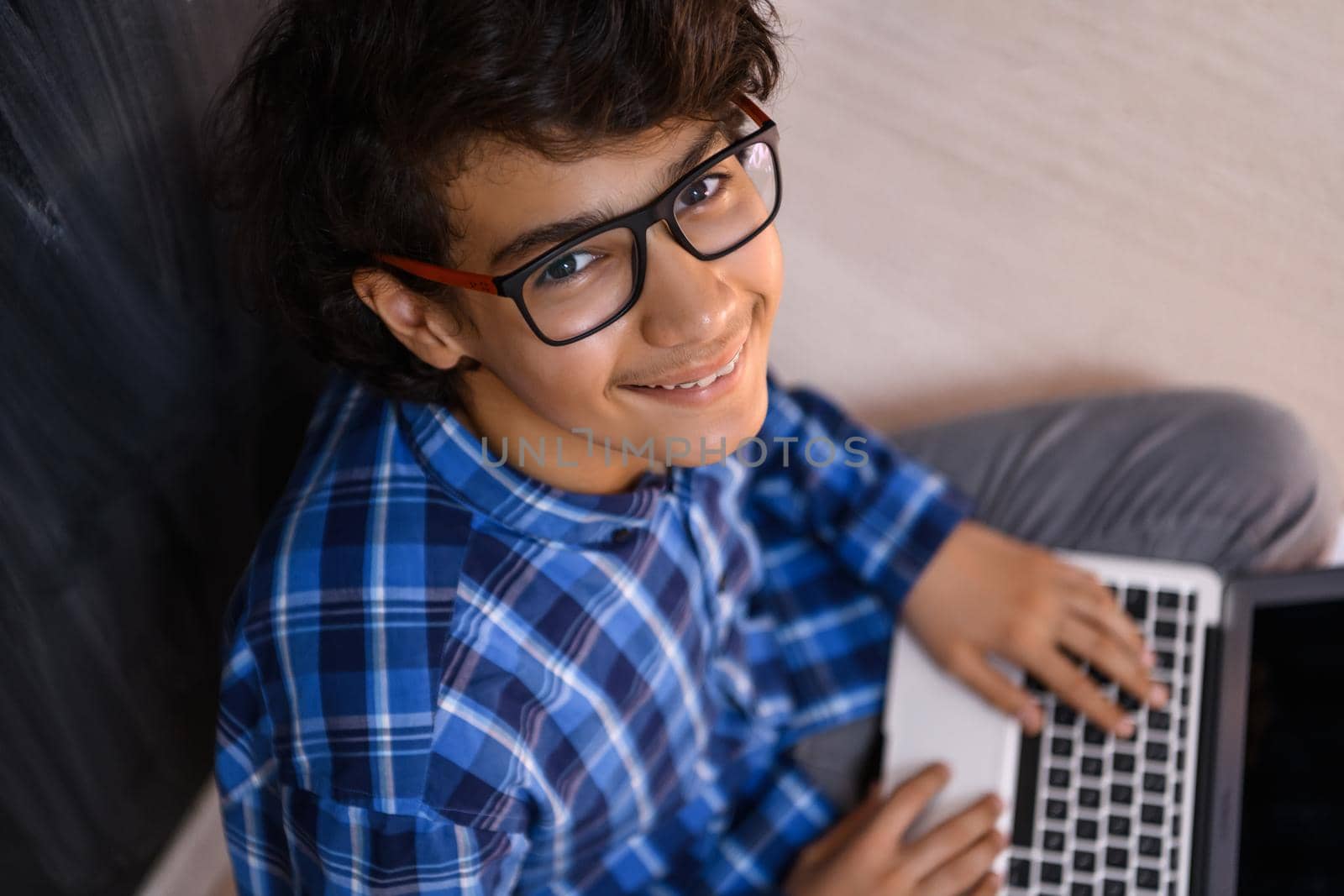 Arab teenager using laptop to work on homework and watch online education while staying at home cause coronavirus pandemic quarantine by dotshock