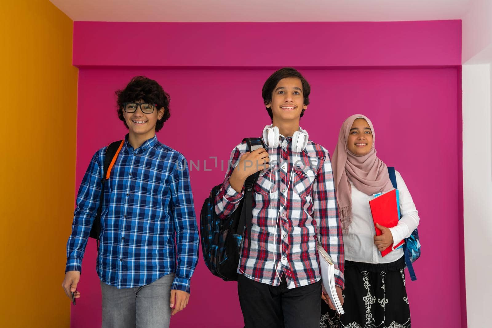 A group of Arab teenagers, a student team walking forward into the future and back to school the concept of a pink background. The concept of successful education for young people. Selective focus. High quality photo