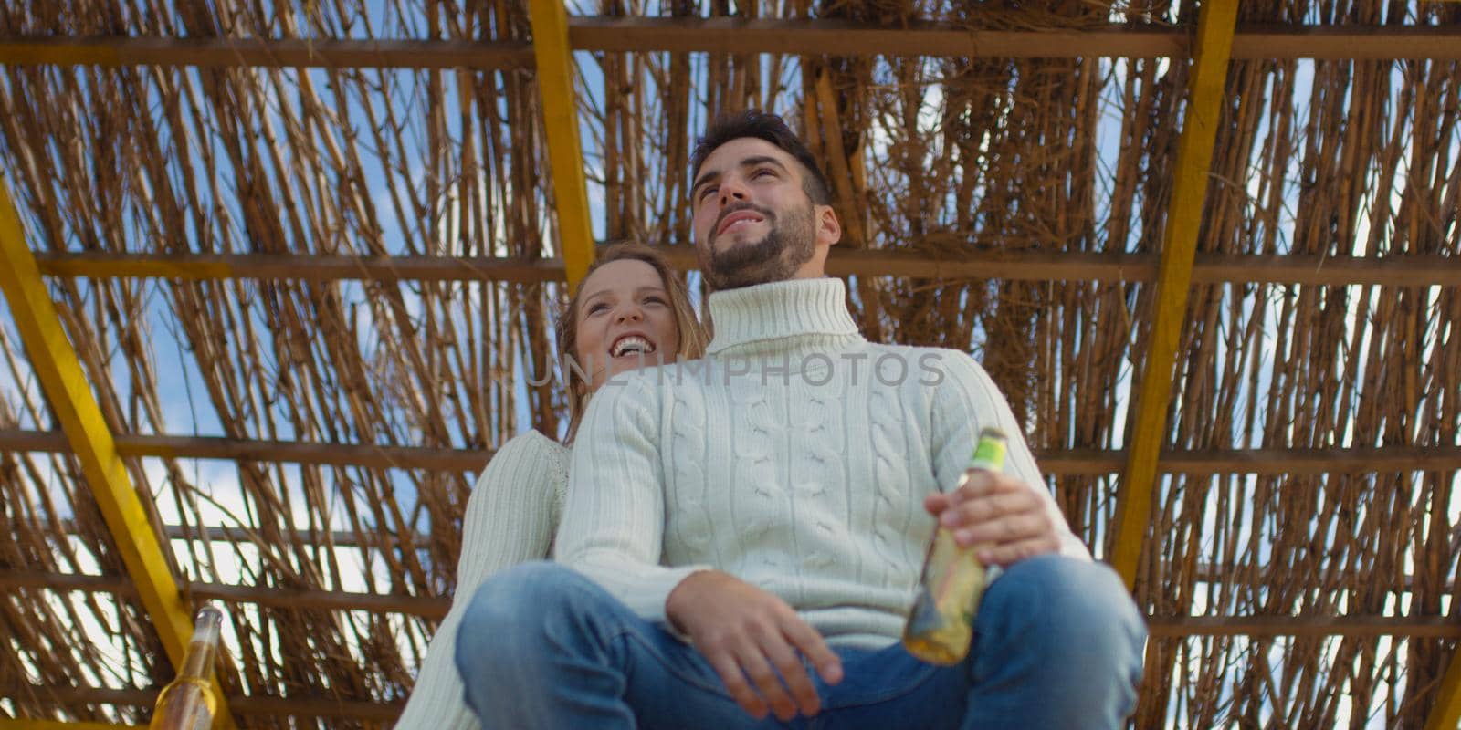 Couple Drinking Beer Together on beach during autumn time