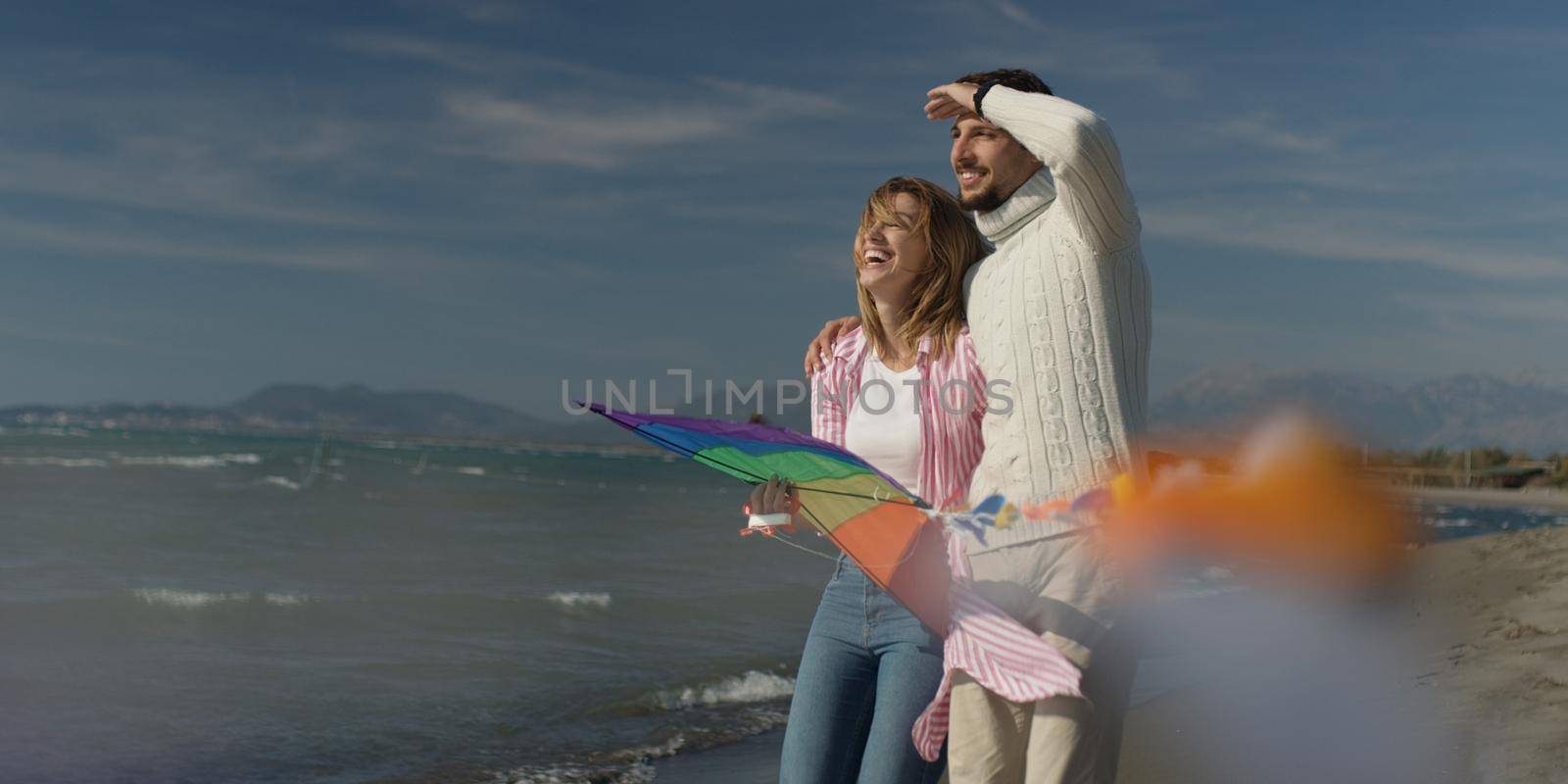 Happy couple having fun with kite on beach by dotshock