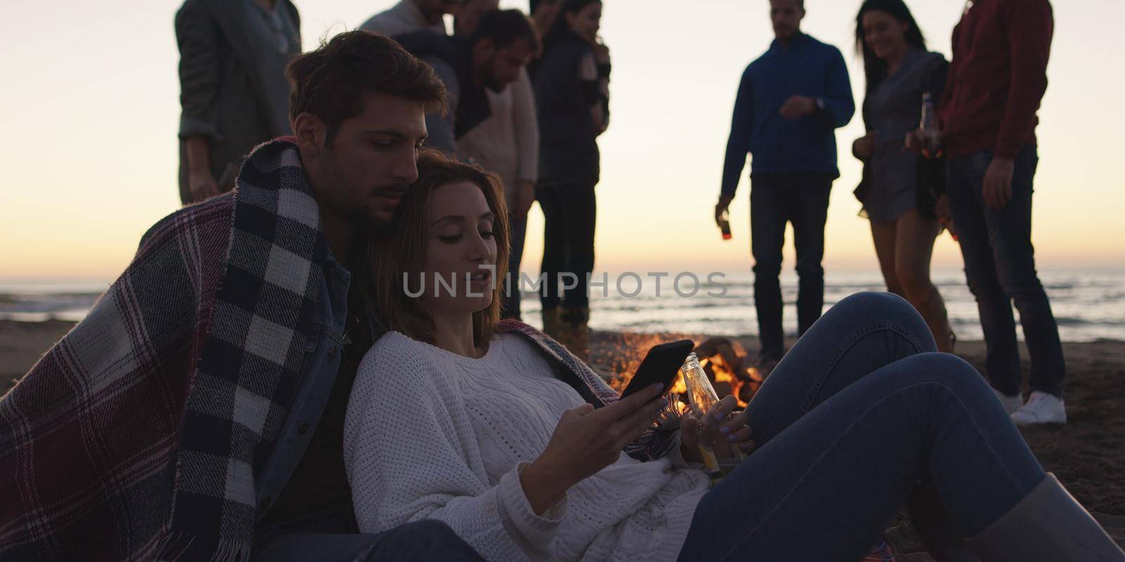 Couple enjoying bonfire with friends on beach by dotshock