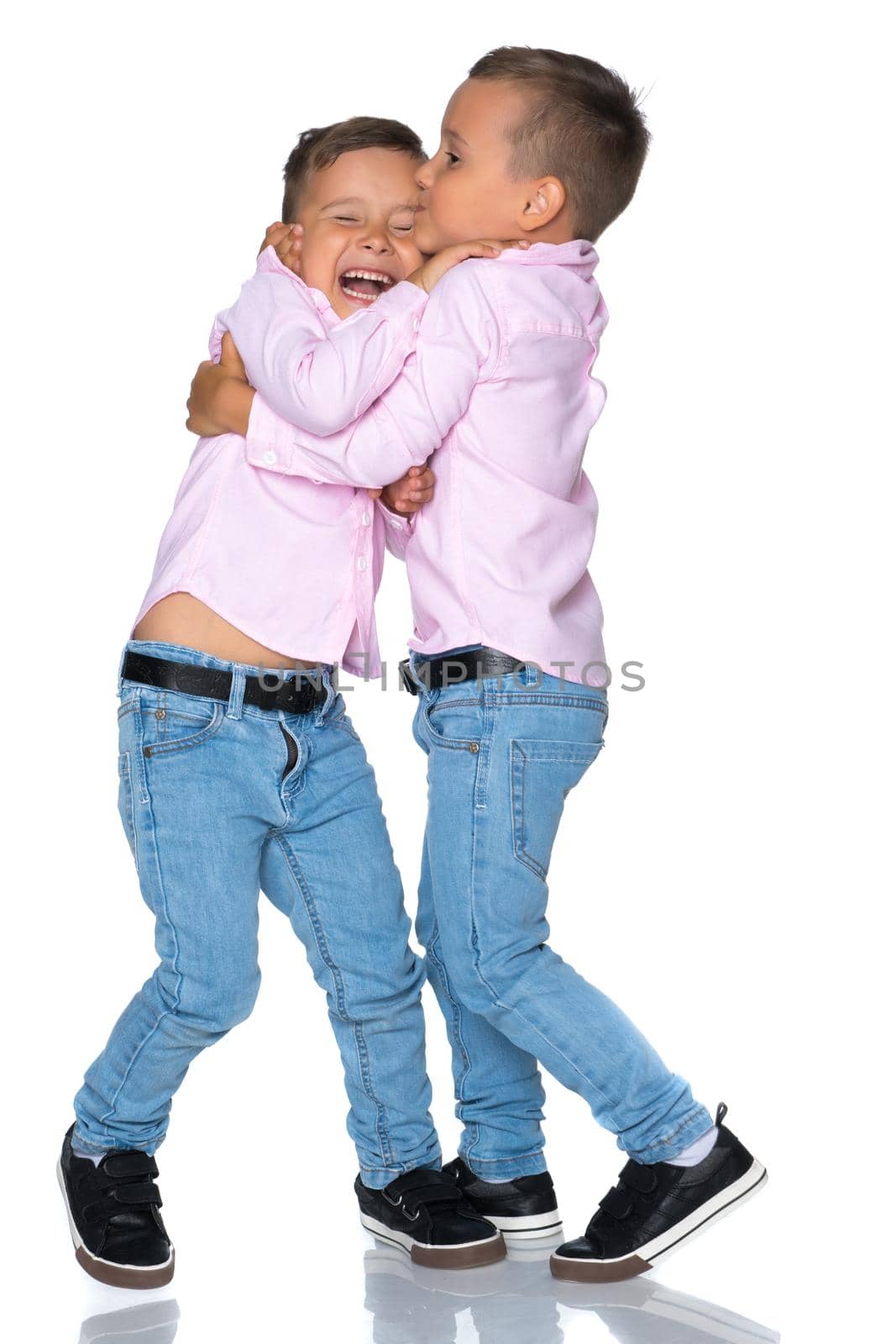 Two cute little boys stand in front of the camera in full growth. The concept of a happy childhood, the development of a child in the family. Isolated on white background.