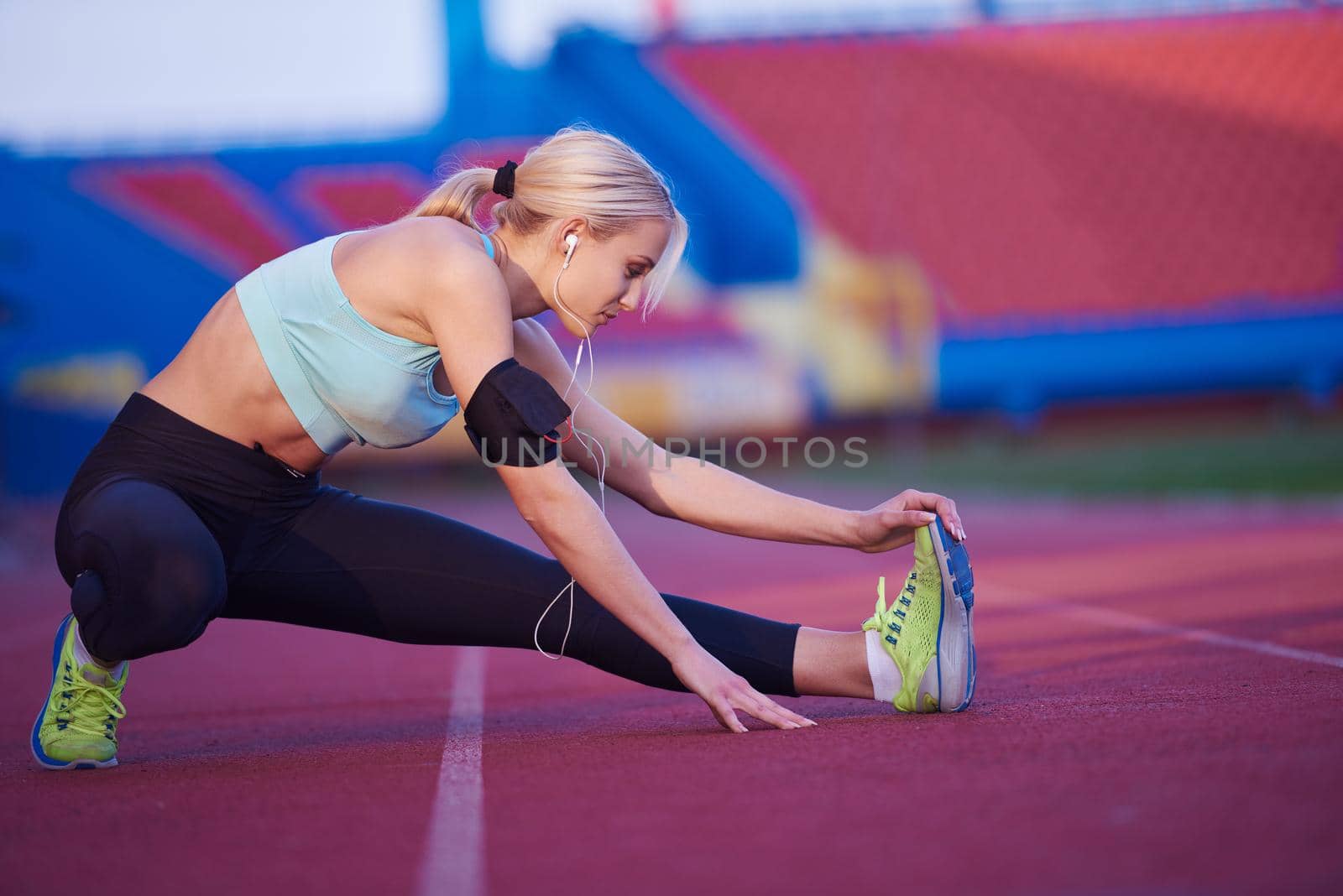 young runner sporty woman relaxing and stretching on athletic race track