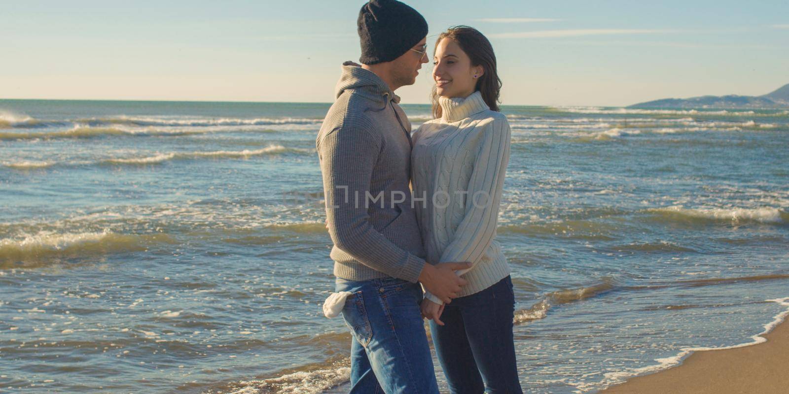 Cool Couple Laughing and hugging In Front Of Beach at beautiful autumn day