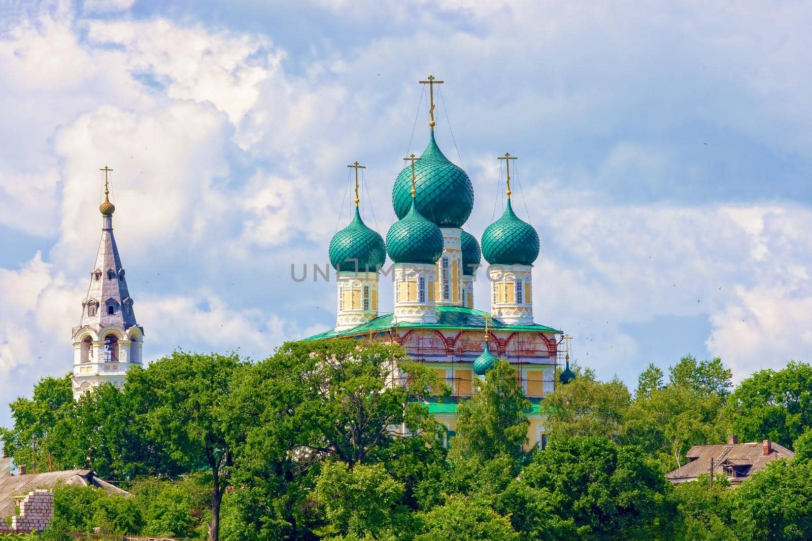 Old Russian monastery in the summer time among the thick green trees, on a sunny day. The concept of the history of Russia, a tourist.
