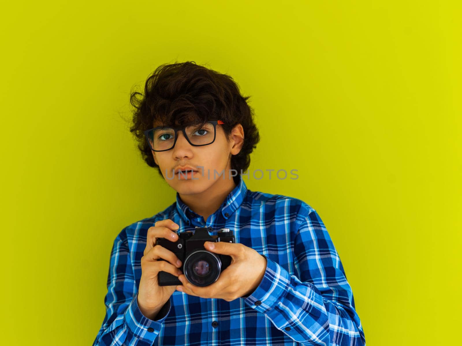 Enthusiastic Arab teen photographer with analog SLR camera on a green background. Selective focus. High quality photo