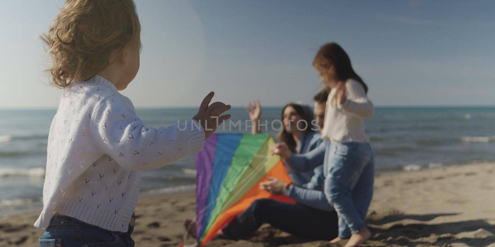 Family with kids resting and having fun at beach during autumn day