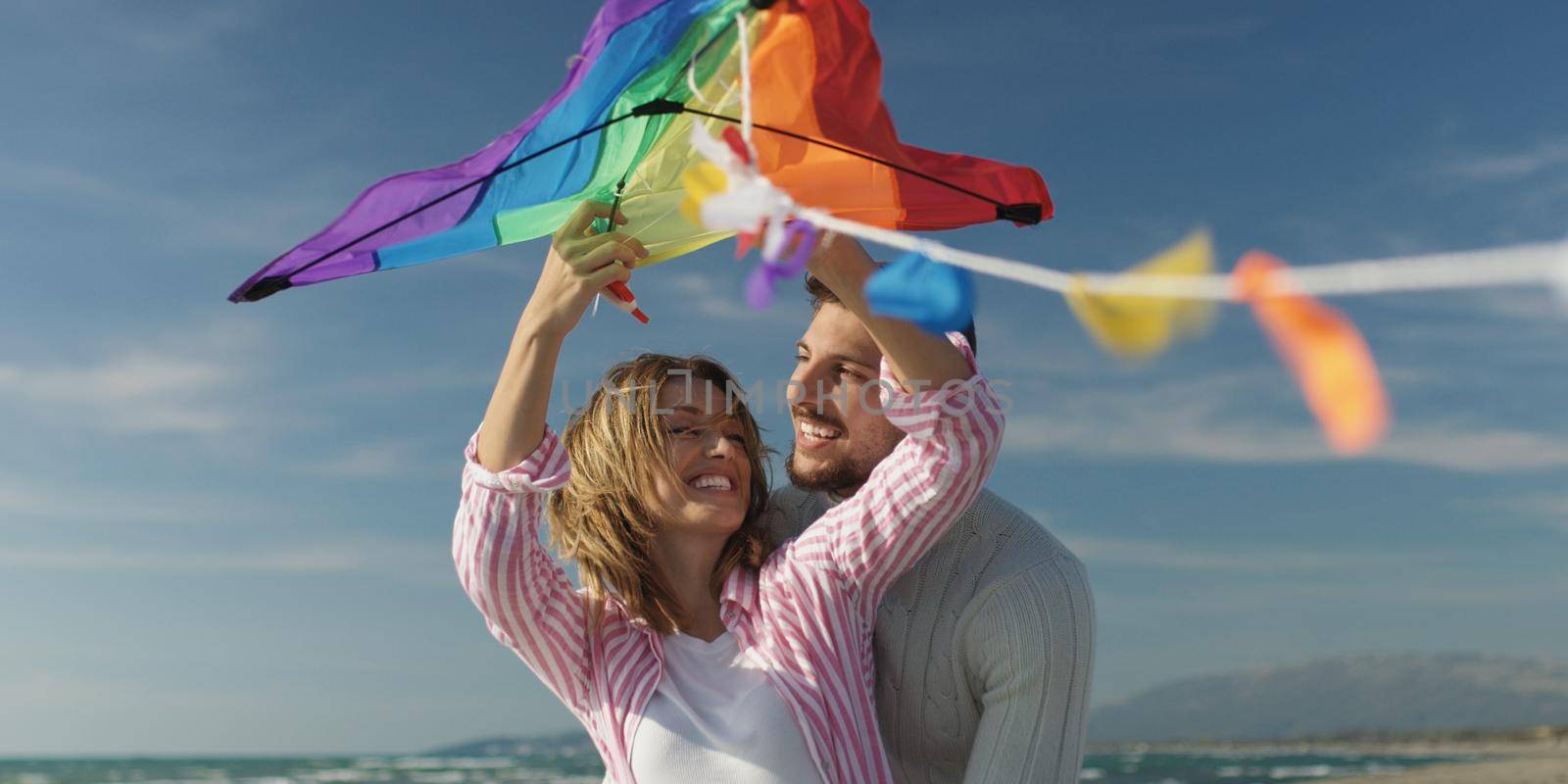 Happy couple having fun with kite on beach by dotshock