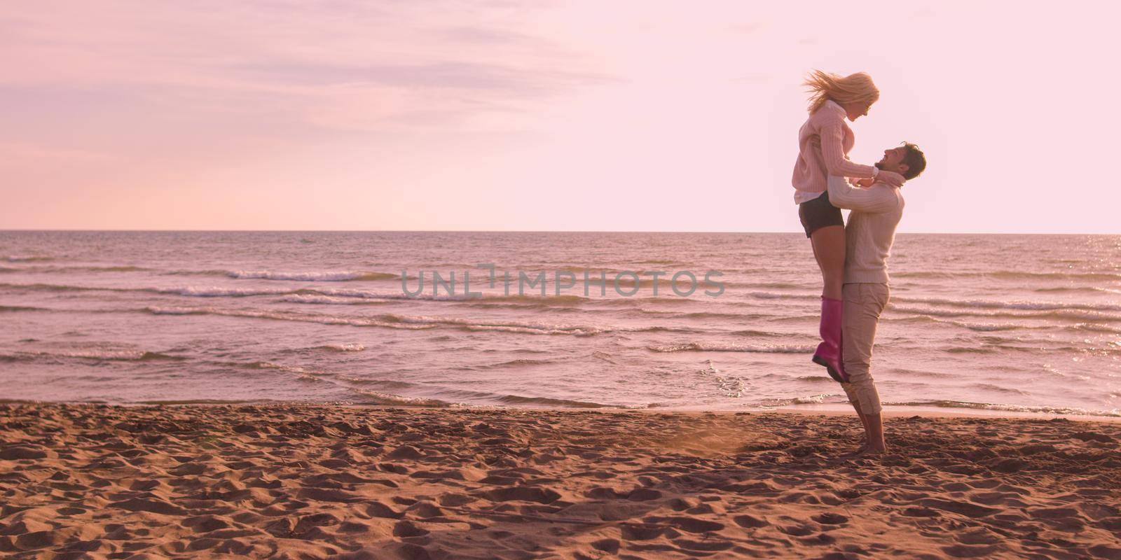 Young couple having fun on beach during autumn sunny day