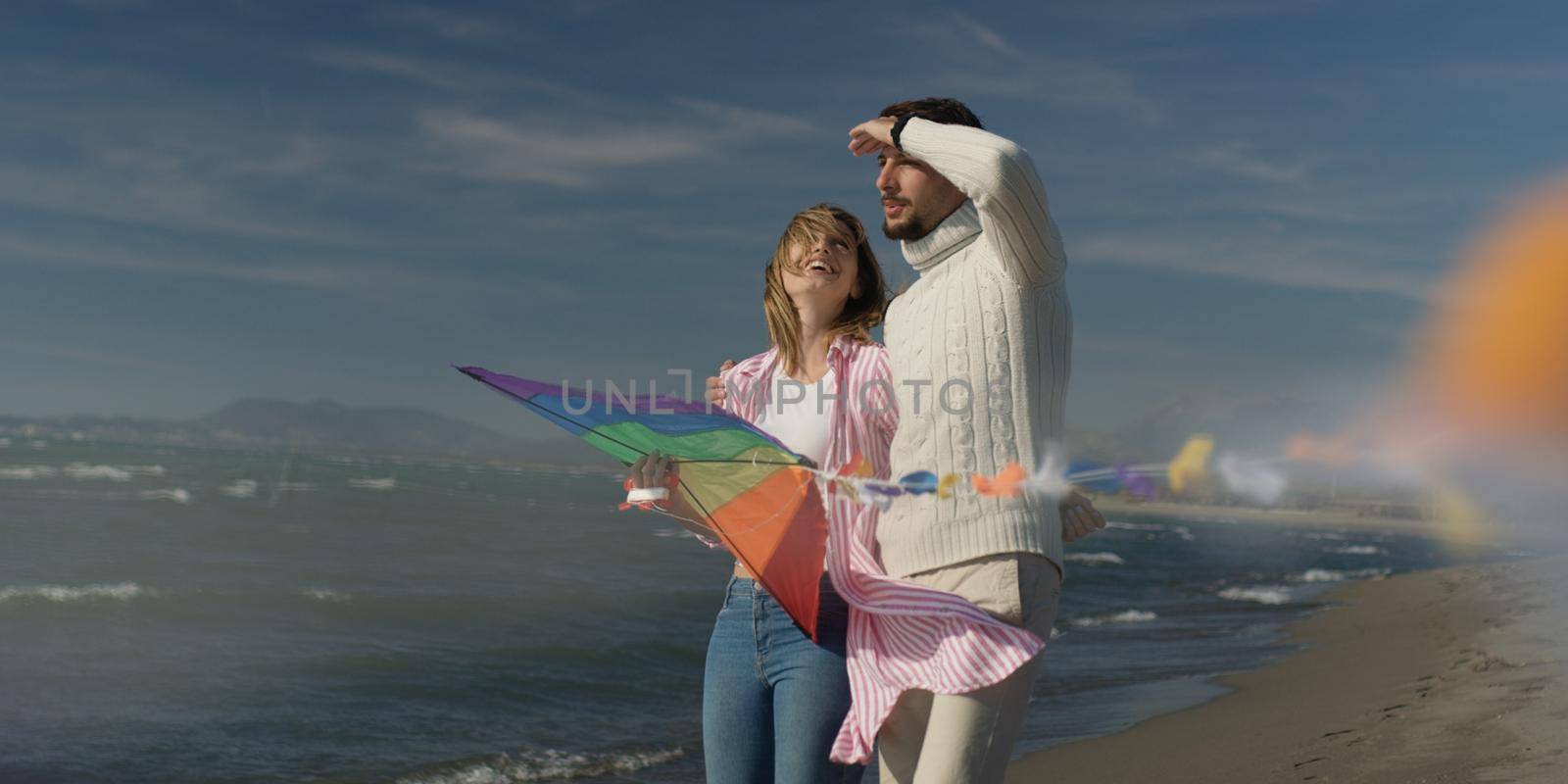 Loving Couple Flying A Kite at Beach and having fun on autumn day