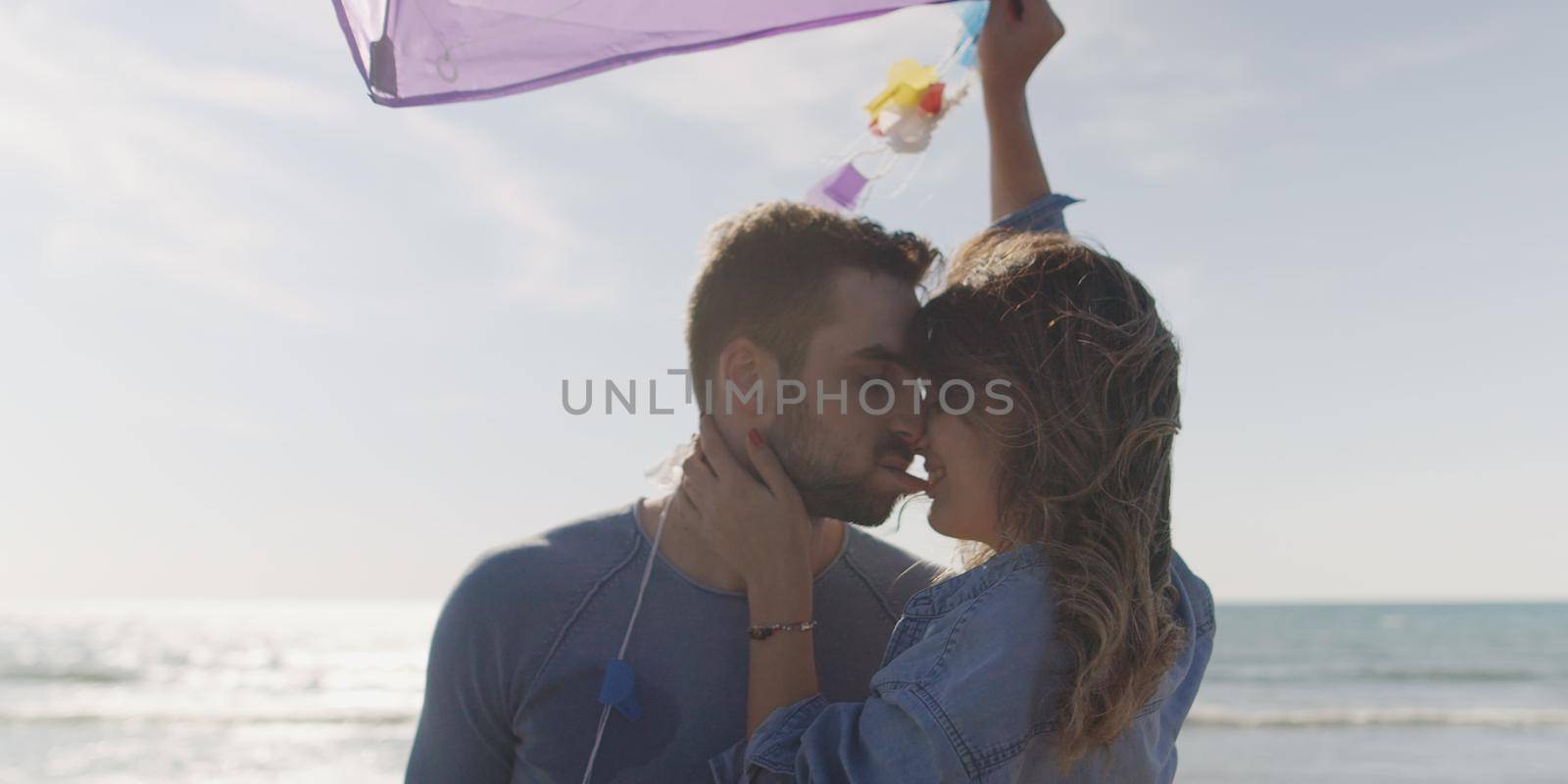 Loving Couple Flying A Kite at Beach and having fun on autumn day