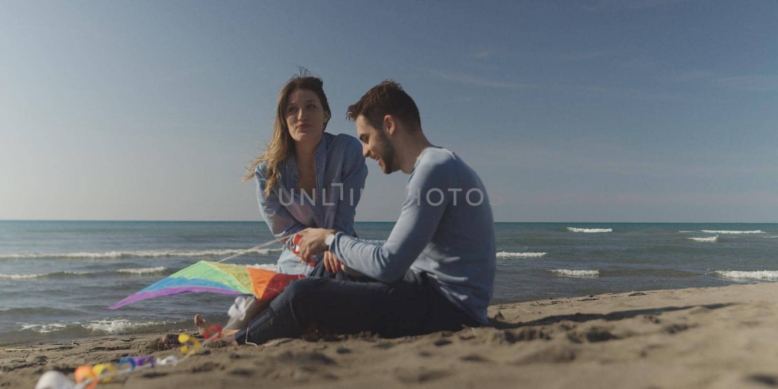 Young Couple having fun and Playing With A Kite On The Beach at autumn day