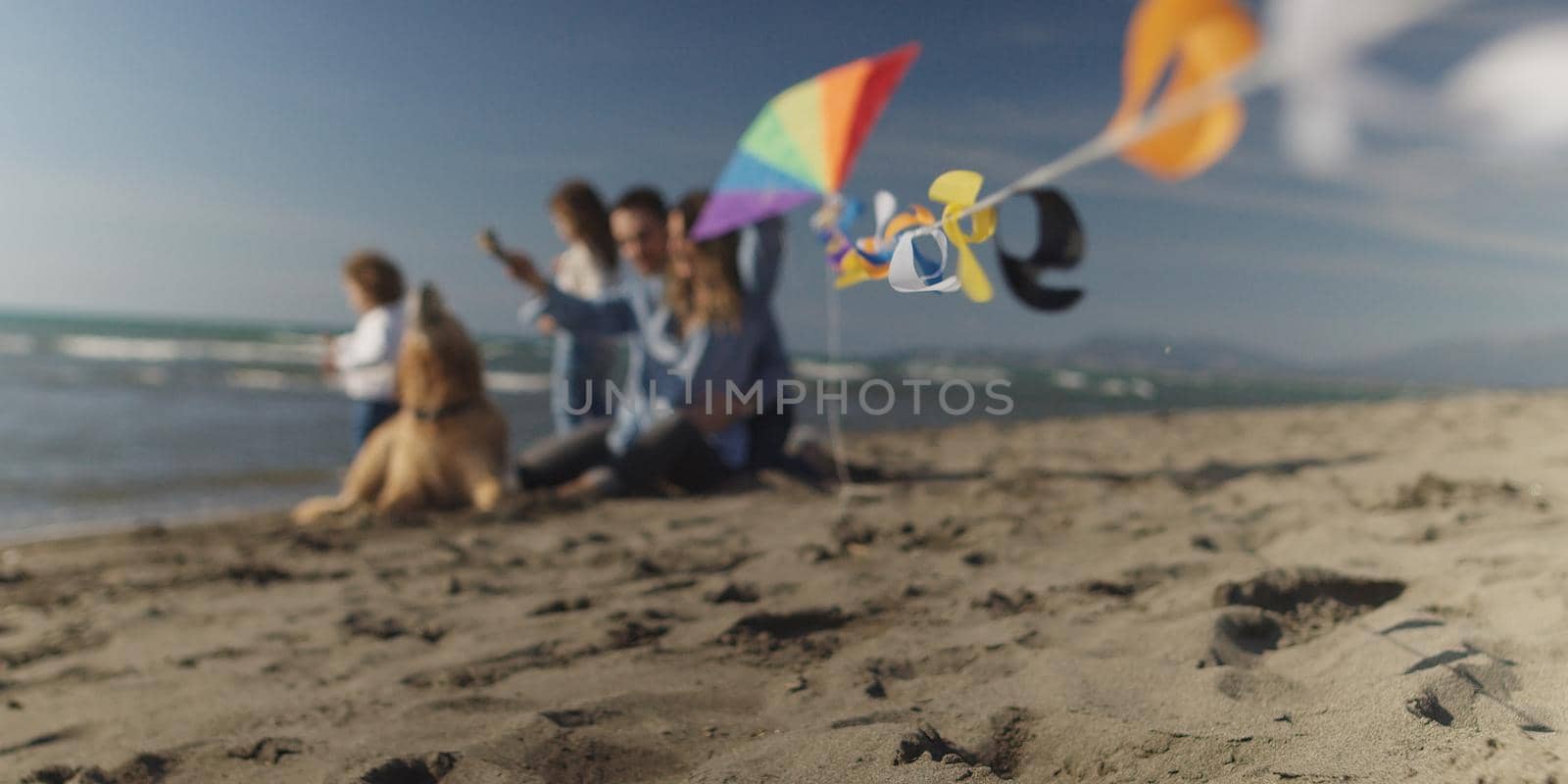 Family with kids resting and having fun at beach during autumn day