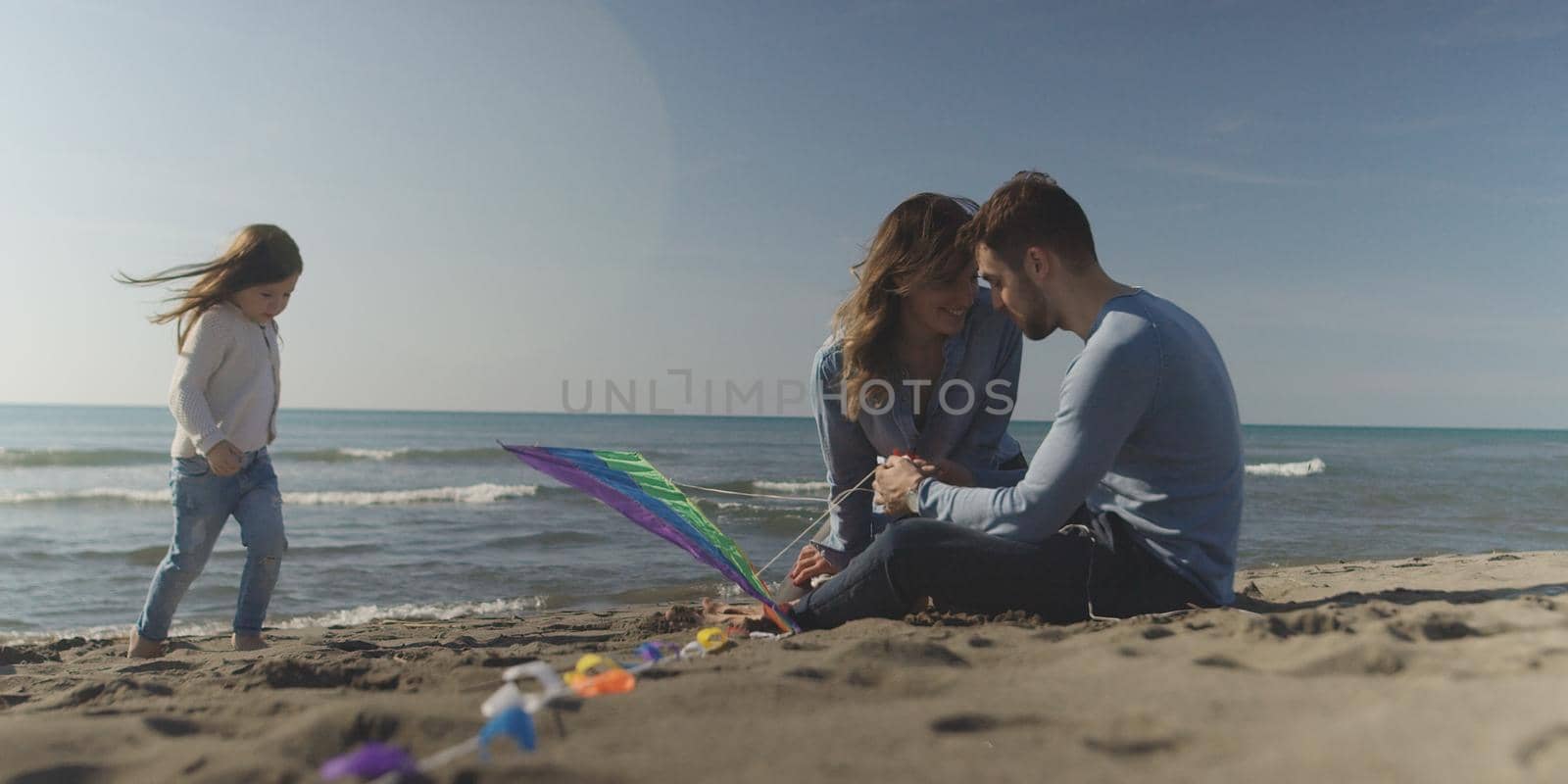 Family with kids resting and having fun at beach during autumn day