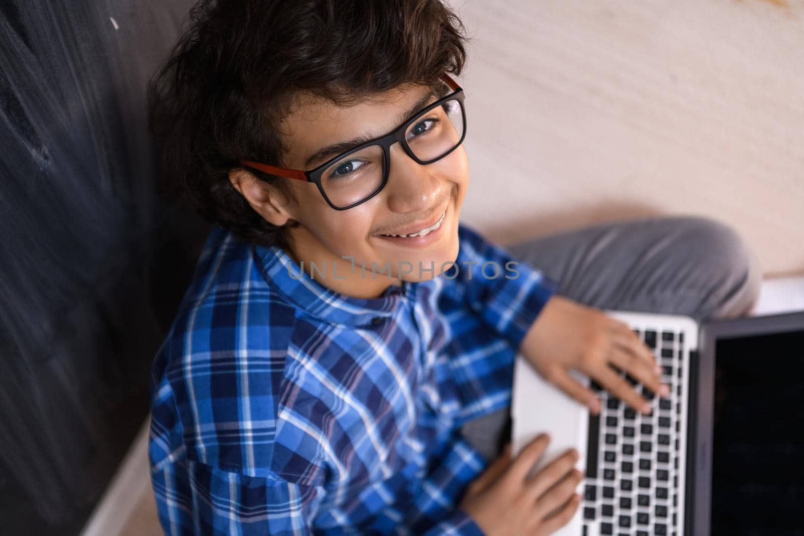 Arab teenager using laptop to work on homework and watch online education while staying at home cause coronavirus pandemic quarantine by dotshock