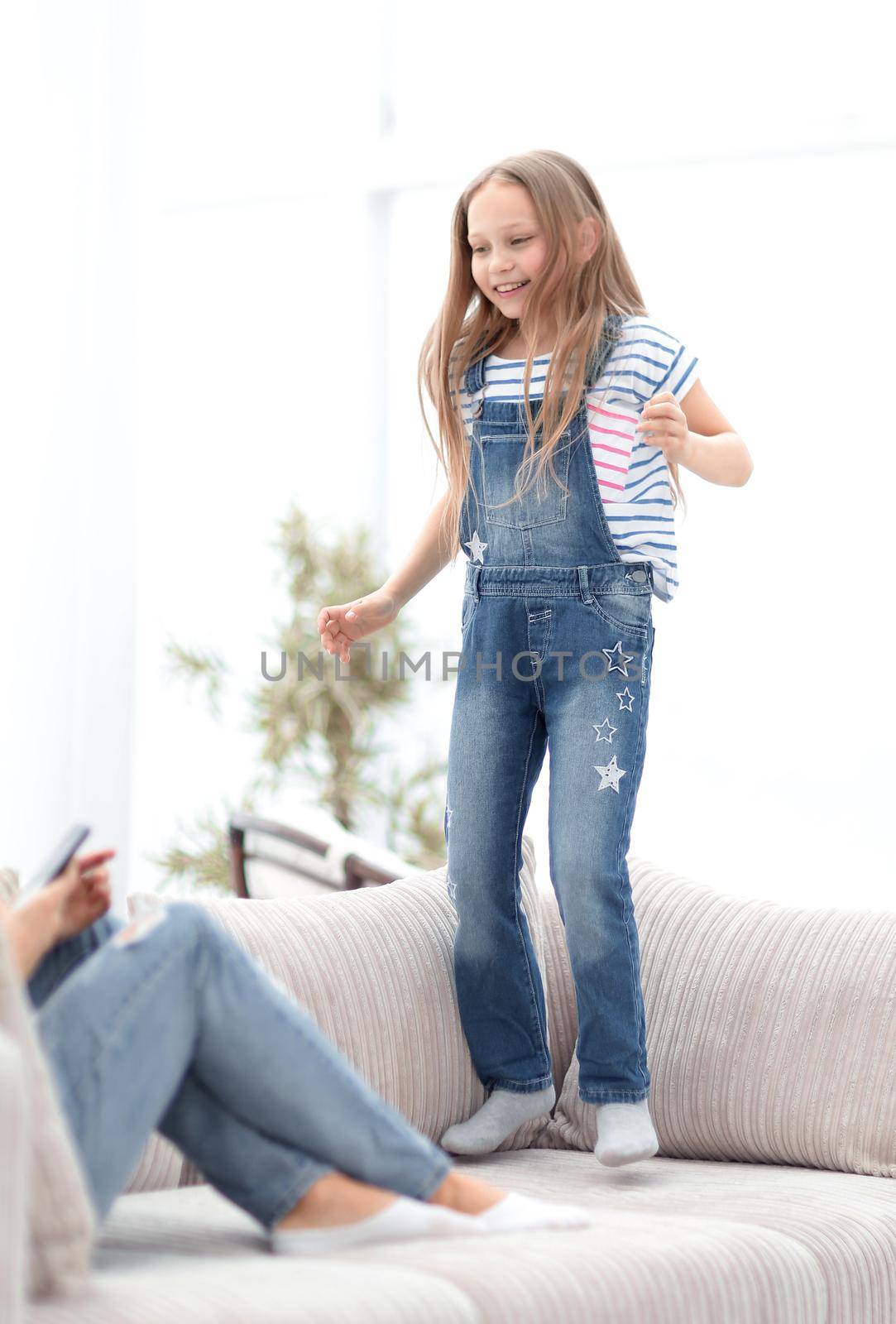 little girl jumping on the couch on the couch in the living room.the concept of children's happiness