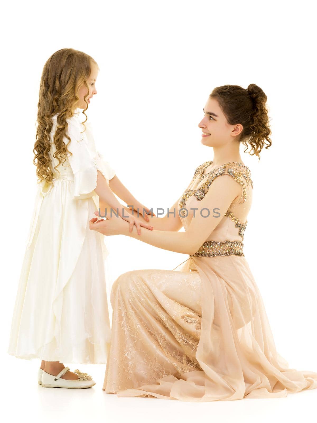 Beautiful young girl hugging her little sister. The concept of a happy childhood, family values. Isolated on white background.