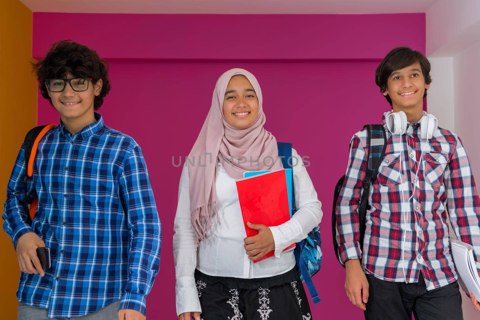A group of Arab teenagers, a student team walking forward into the future and back to school the concept of a pink background. The concept of successful education for young people. Selective focus by dotshock
