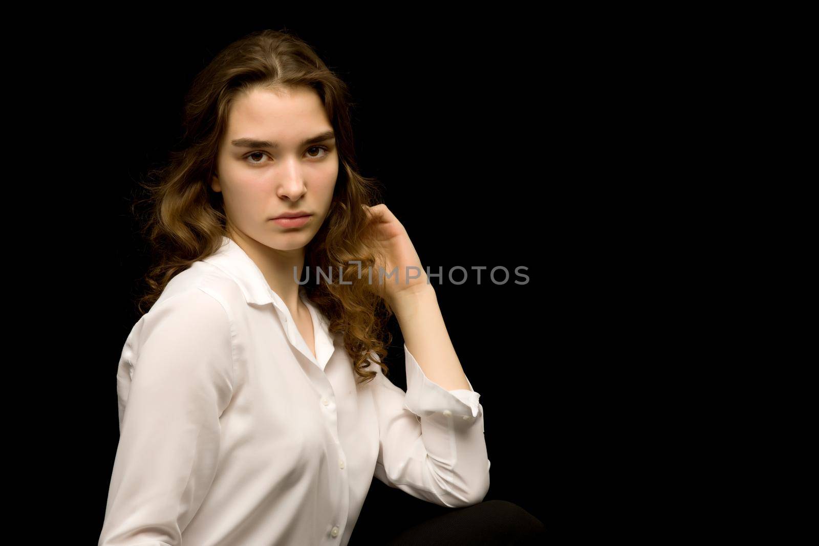 Beautiful teenage girl, studio photo. The concept of fashion and style. On a black background.