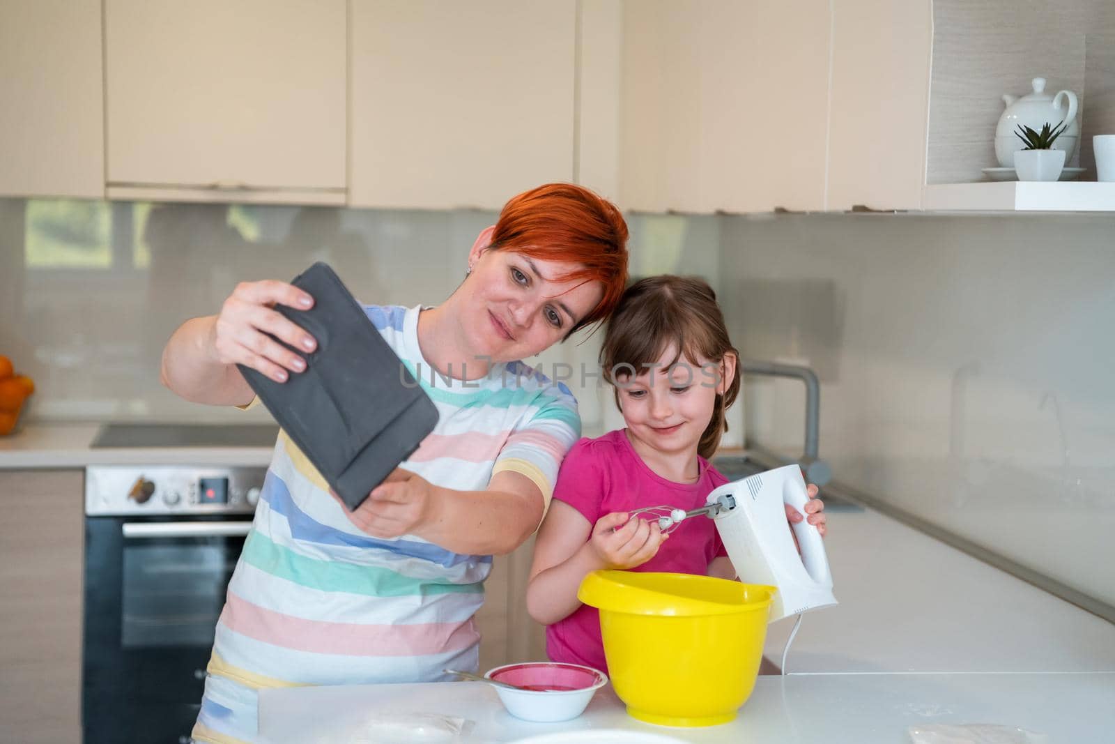 little girl and mom making tastz cake in kithen, family having fun at home 