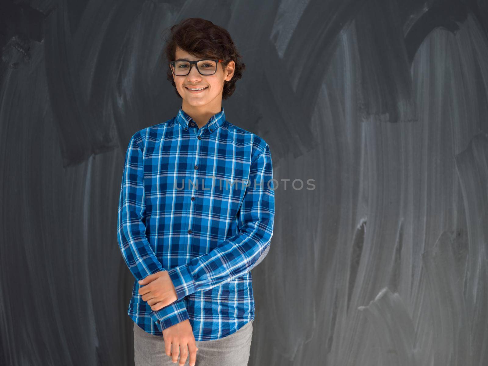 a portrait of a young Arab teenager standing in front of a school blackboard. High quality photo