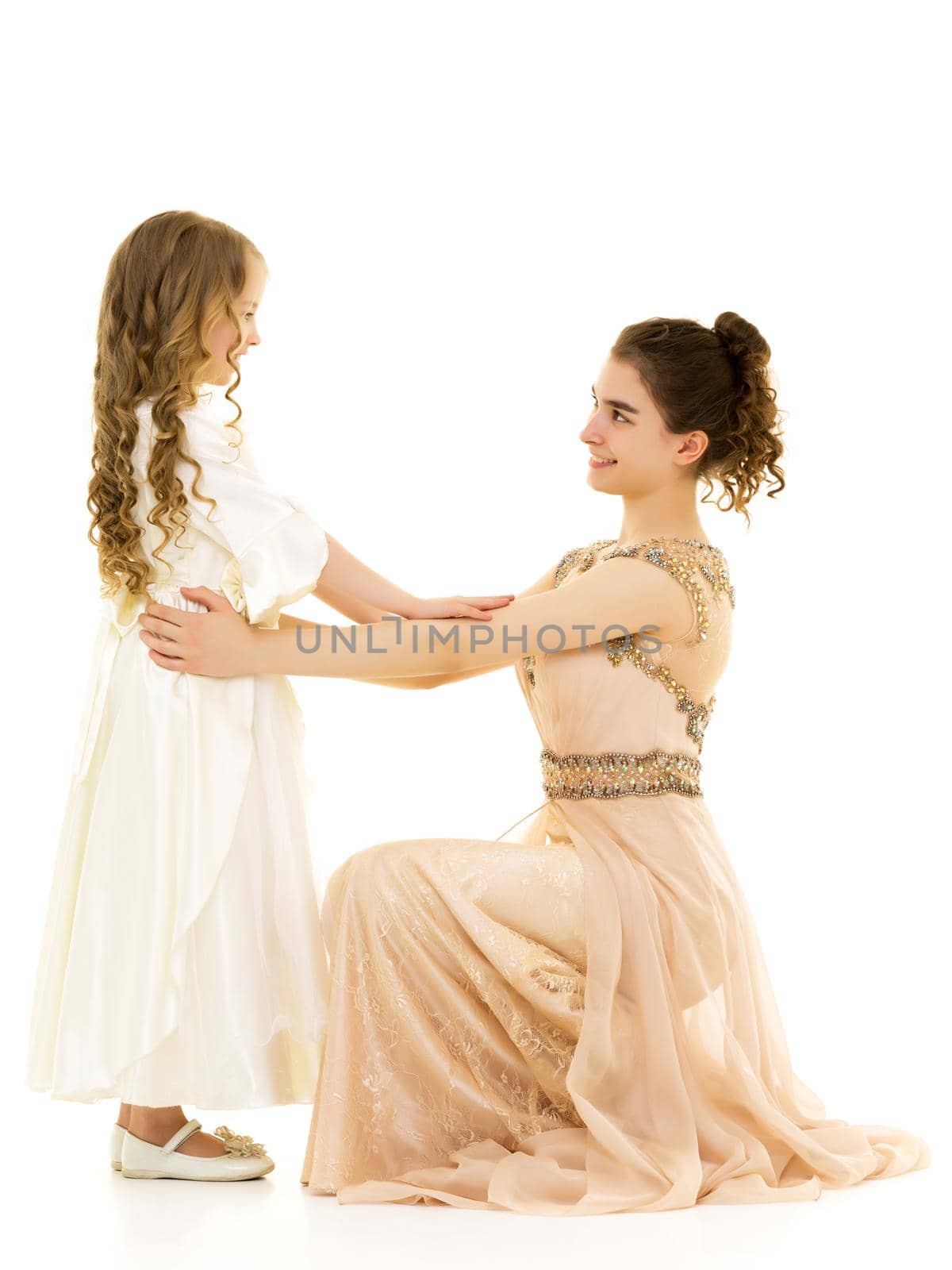 Beautiful young girl hugging her little sister. The concept of a happy childhood, family values. Isolated on white background.