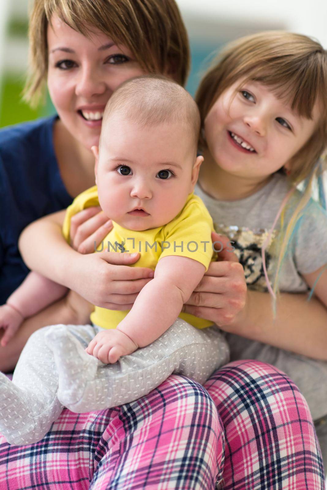 Happy loving family. portrait of young mother with  her kids little girl and baby boy hugging each other while spending time together at home