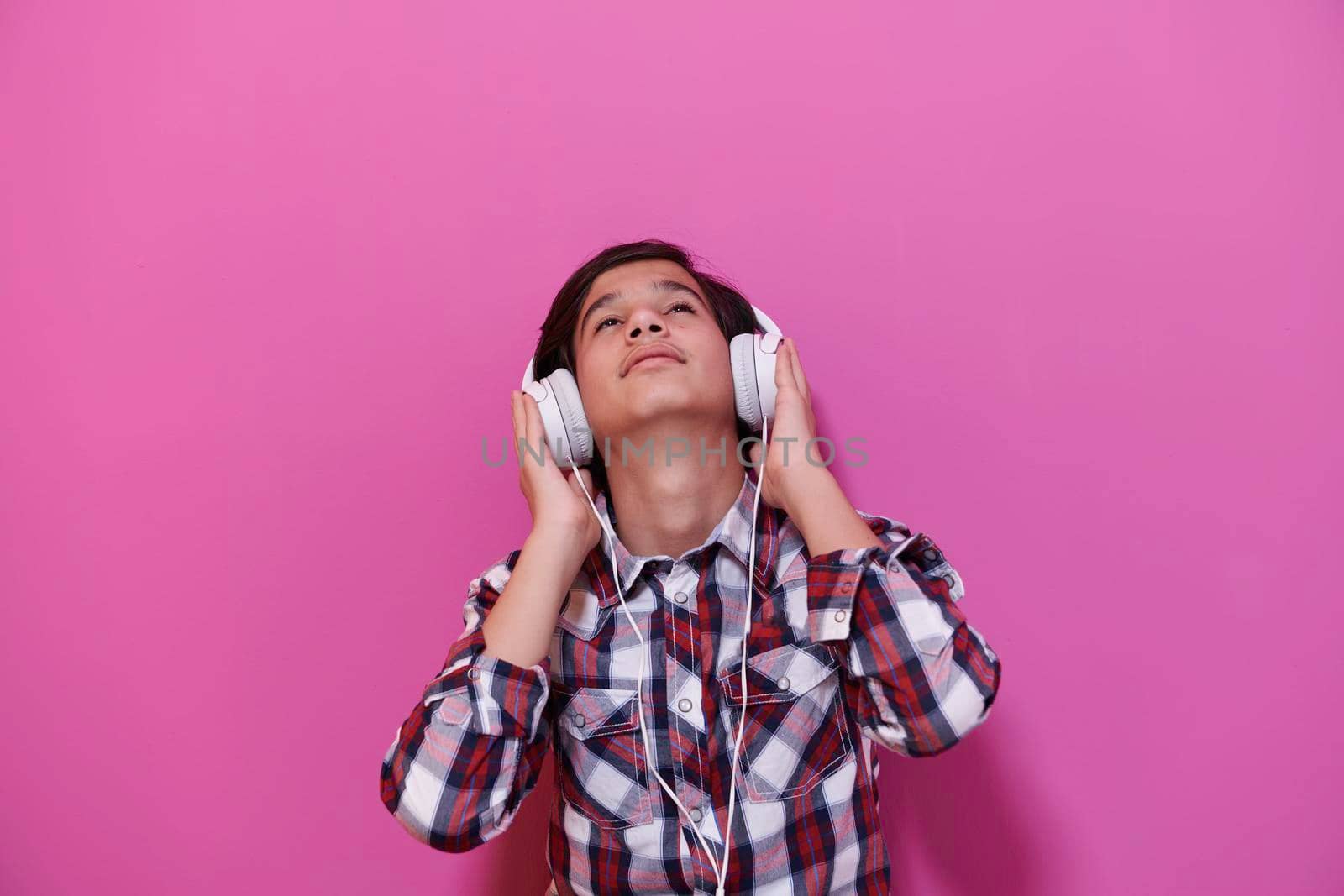 Arabic Teenage Boy Wearing Headphones And Listening To Music pink background