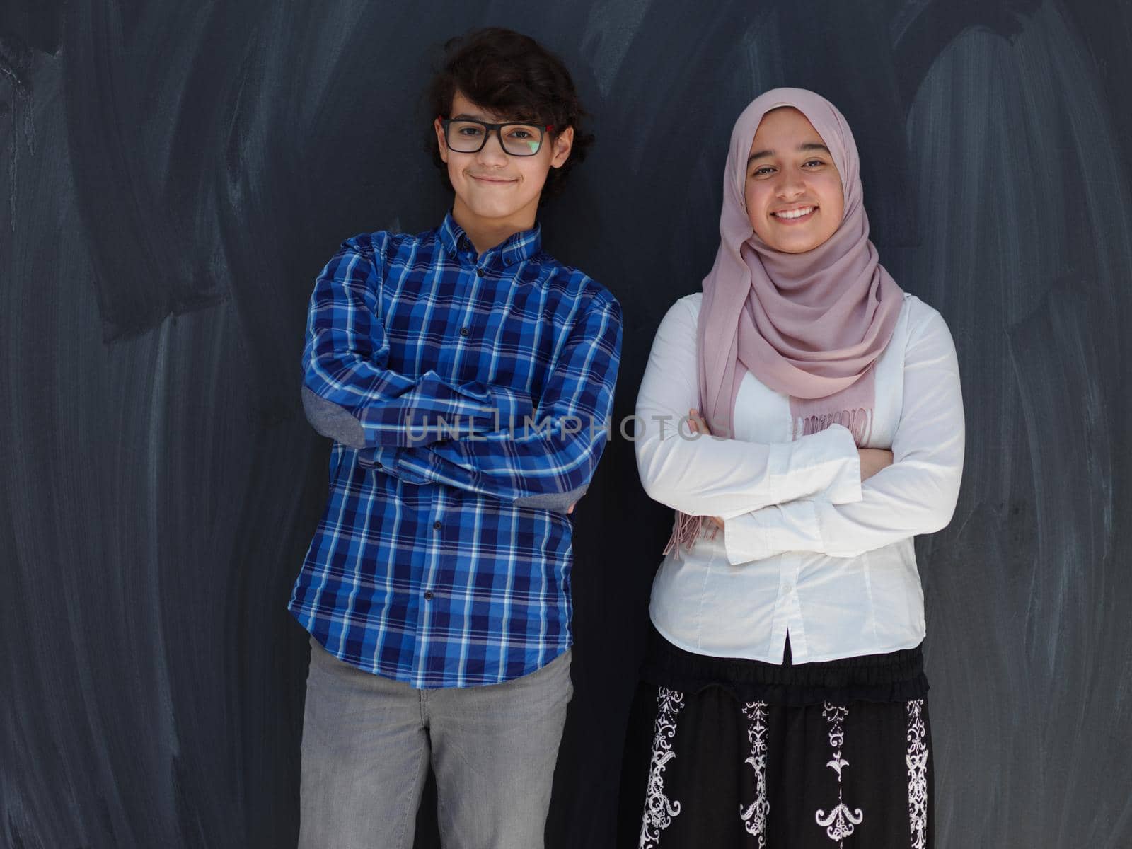 portrait of smart looking arab teens  against black chalkboard  background in school